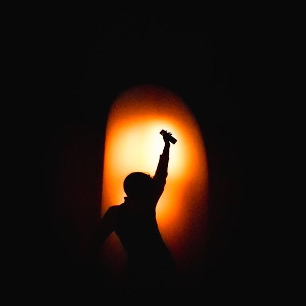 Silhouette of a woman in a yoga pose against a dark background with orange light.