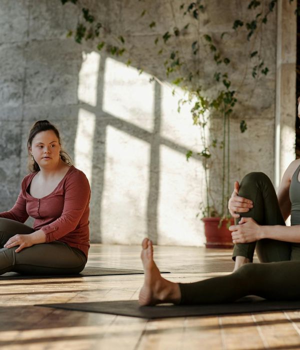 Woman performing a gentle stretching exercise in a sunlit room.